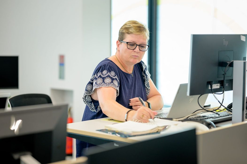 Person reviewing printed notes beside a laptop while researching a topic