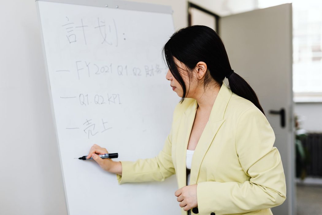 A person drawing a flowchart of boxes and arrows on a whiteboard